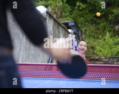 (190601) -- BEIJING, June 1, 2019 (Xinhua) -- Wang Beihai (L) and Chen Weiyu play table tennis at the Sanhe Elementary School in Dabaidi Township of Ruijin City, east China s Jiangxi Province, May 7, 2019. The Sanhe Elementary School, located deep in the mountains of Ruijin, has only one teacher, 46-year-old Wang Beihai, and one student Chen Weiyu, a 9-year-old boy from a poverty-stricken family. The student Chen Weiyu, who lived with his grandapa, used to stude at a school about 20 kilometers away from his home. His grandpa had to take him to and from school by driving a tractor every day. Lo Stock Photo