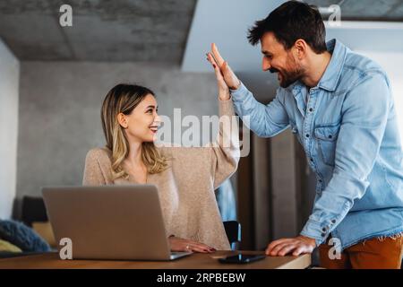 Couple of young designers working at modern home office, two coworkers discussing fun project Stock Photo