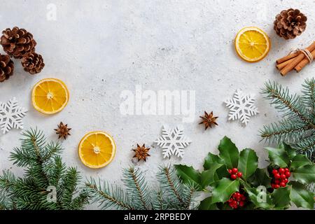 Christmas decorations with holly berries and tree branches on table. Stock Photo