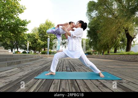 Luannan County, China - June 21, 2019: A lady and a little girl practicing yoga together, Luannan County, Hebei Province, China. In recent years, yoga Stock Photo