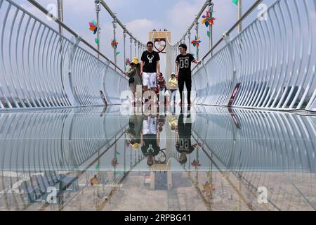 (190608) -- NANTONG, June 8, 2019 (Xinhua) -- Tourists walk on a glass-bottomed bridge at a scenic area of Nantong, east China s Jiangsu Province, June 8, 2019. (Xinhua/Xu Congjun) CHINA-DRAGON BOAT FESTIVAL-HOLIDAY (CN) PUBLICATIONxNOTxINxCHN Stock Photo