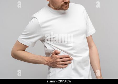 Closeup hand man touches unwell body side suffers from unbearable pain isolated studio background. Stock Photo