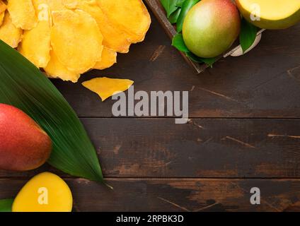 Large dried mango pieces on wooden board with fresh raw fruits.Top view. Stock Photo