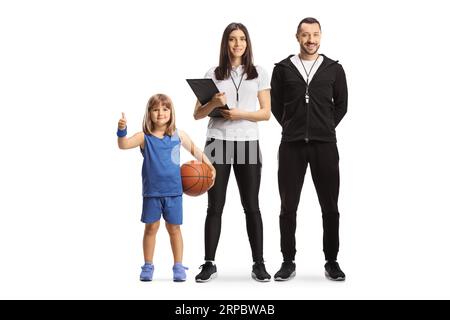 Male and female coaches posing with a girl holding a basketball and gesturing thumbs up isolated on white background Stock Photo