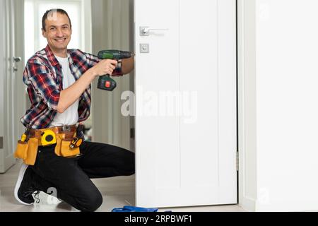 Master with screwdriver installs door hinges. Stock Photo