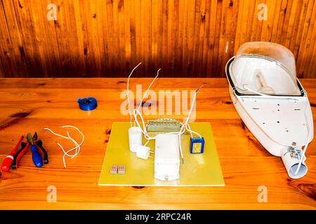 A large white disassembled street lamp with an electrical circuit with wires and spare parts, installation equipment, pliers, blue electrical tape, sc Stock Photo