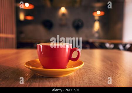 Red cup of tasty cappuccino on table in a cafe Stock Photo