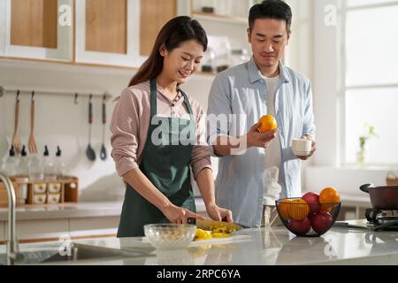 loving young asian couple chatting talking conversing in kitchen at home while preparing food Stock Photo