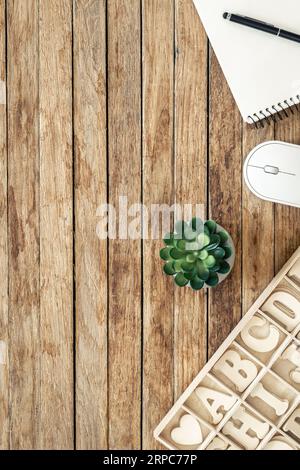 Set of wooden letters of the English alphabet and a notepad on a wooden background, top view. Stock Photo