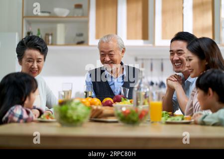 multi generational asian family chatting while having meal together at home Stock Photo