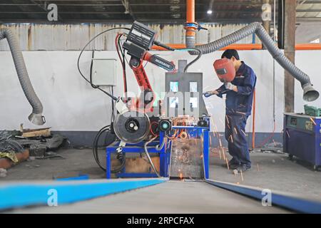 Luannan County, China - June 21, 2019: Workers inspect the work of intelligent welding robots in a factory, Luannan County, Hebei Province, China. At Stock Photo