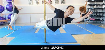 (190711) -- JILIN, July 11, 2019 -- Jiang Zhijun (C) and her team members practice pole dancing in the dance room in Jilin City, northeast China s Jilin Province, July 10, 2019. A group of dama, refering to the legions of usually middle aged women, formed a team of pole dancing in Jinlin City, northeast China s Jilin Province in 2016. The team has eight members with an average age of 64. Pole dancing is known for its softness and strength, says Jiang Zhijun, the 68-year-old team leader. We started with basic strength training, then went forward to perform high-level moves gradually. The team c Stock Photo