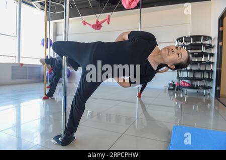 (190711) -- JILIN, July 11, 2019 -- Jiang Zhijun and her team members stretch in the dance room in Jilin City, northeast China s Jilin Province, July 10, 2019. A group of dama, refering to the legions of usually middle aged women, formed a team of pole dancing in Jinlin City, northeast China s Jilin Province in 2016. The team has eight members with an average age of 64. Pole dancing is known for its softness and strength, says Jiang Zhijun, the 68-year-old team leader. We started with basic strength training, then went forward to perform high-level moves gradually. The team competed in many do Stock Photo