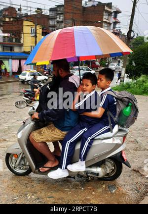 (190712) -- KATHMANDU, July 12, 2019 -- A man takes his children towards school during rainfall in Kathmandu, Nepal, July 12, 2019. Nepal has been hit by heavy rainfall since Thursday evening. ) NEPAL-KATHMANDU-MONSOON-RAINFALL sunilxsharma PUBLICATIONxNOTxINxCHN Stock Photo