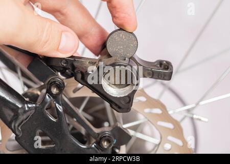 new brake pads in hand on the background of a bicycle brake caliper. Replacement of brake pads Stock Photo