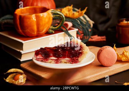 Aesthetics cozy home breakfast - cherry pie, cup of coffee in shape of pumpkin, macaroons, candle and winter cherry. Hygge home aesthetic. Stock Photo