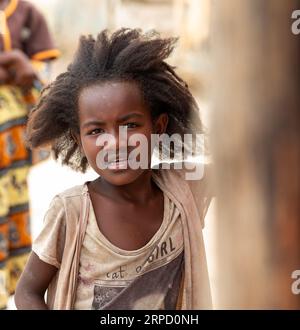 Bekopaka - Antsalova, Madagascar- November 6. 2022: Small cute Malagasy girl with long hair , happy little dancer on celebration in village Bekopaka, Stock Photo