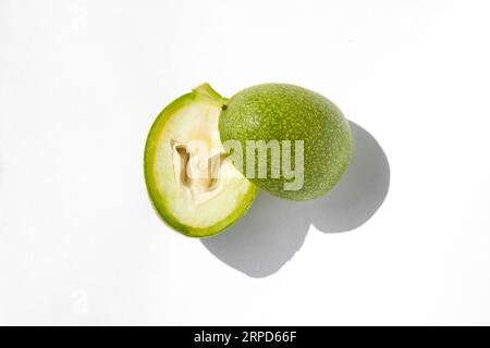 The green outer shells of the unripe walnuts are cut in half, unripe green walnuts Stock Photo