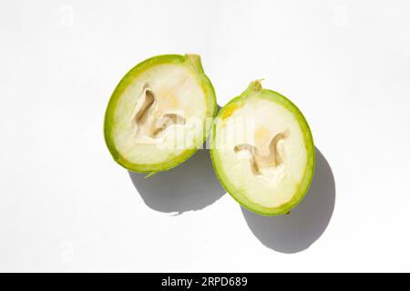 The green outer shells of the unripe walnuts are cut in half, unripe green walnuts Stock Photo