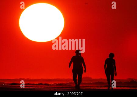 Isle Of Palms, United States. 04th Sep, 2023. A couple walks down the beach silhouetted by the sunrise, as crowds rush to the last days of beach holidays on Labor Day, September 4, 2023 in Isle of Palms, South Carolina. Credit: Richard Ellis/Richard Ellis/Alamy Live News Stock Photo