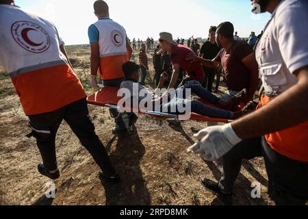 (190726) -- GAZA, July 26, 2019 (Xinhua) -- Palestinian medics carry a wounded man during clashes with Israeli troops near the Gaza-Israel border, east of Gaza City, July 26, 2019. At least 56 Palestinians were injured on Friday during clashes with Israeli soldiers in eastern Gaza Strip, close to the border with Israel, medics said. (Str/Xinhua) MIDEAST-GAZA-CLASHES PUBLICATIONxNOTxINxCHN Stock Photo