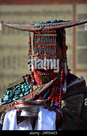 (190728) -- LHASA, July 28, 2019 -- A woman wearing Burang clothes presents highland barley wine to visitors in Burang County of Ali, southwest China s Tibet Autonomous Region, July 22, 2019. Burang clothes, traditional wearing in Burang County of Ali, has a history of more than 1,000 years. One suit may weigh about 25 kilograms because it is decorated with gold, silver, pearls and other jewels. ) CHINA-TIBET-ALI-BURANG CLOTHES (CN) Chogo PUBLICATIONxNOTxINxCHN Stock Photo