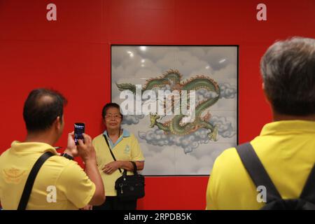 (190729) -- BANGKOK, July 29, 2019 -- A woman poses for photos with a decorative painting at Wat Mangkon station along the new stretch of Bangkok s MRT Blue Line in Bangkok, Thailand, July 29, 2019. Bangkok s MRT Blue Line rail system started a two-month trial runs on a new stretch since Monday, during which commuters can take a ride free of charge to the city s famous tourist attractions such as Chinatown, the Grand Palace and Temple of the Reclining Buddha. ) THAILAND-BANGKOK-METRO-OPEN YangxZhou PUBLICATIONxNOTxINxCHN Stock Photo