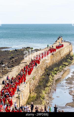 New students at the University of St Andrews wearing red robes take part in the traditional Pier Walk along the harbour walls of St Andrews Stock Photo
