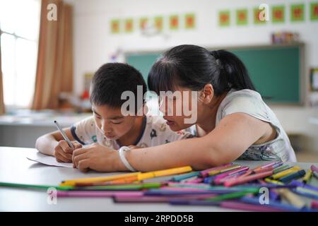 (190731) -- NANCHANG, July 31, 2019 -- Liu Xiaoqing (R) teaches a deaf-mute student to draw pictures at the Luxi County Special Education School in Luxi County of Pingxiang, east China s Jiangxi Province, July 3, 2019. When the Luxi County Special Education School was established in 1997, Liu Xiaoqing, then a normal university graduate, applied for a post there without hesitation. Working as a special education teacher has been challenging, as Liu s students need far more attention than their peers without physical or mental disabilities. But Liu stayed on her post for 22 years helping her stu Stock Photo