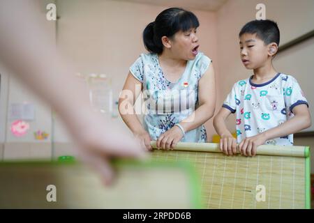 (190731) -- NANCHANG, July 31, 2019 -- Liu Xiaoqing helps a student make bed at the Luxi County Special Education School in Luxi County of Pingxiang, east China s Jiangxi Province, July 3, 2019. When the Luxi County Special Education School was established in 1997, Liu Xiaoqing, then a normal university graduate, applied for a post there without hesitation. Working as a special education teacher has been challenging, as Liu s students need far more attention than their peers without physical or mental disabilities. But Liu stayed on her post for 22 years helping her students improve with vario Stock Photo