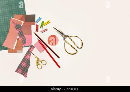 A gold plated stork scissors, pencils and pieces of colored papers on a white background with copy space Stock Photo