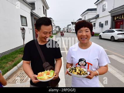 (190803) -- HEBI, Aug. 3, 2019 -- Two villagers take their cooking dishes to the final rounds of a rural cuisine competition in Gangpo Village of Qibin District, Hebi, central China s Henan Province, Aug. 3, 2019. The rural cuisine competition is part of Gangpo Village s vision to develop rural tourism by taking advantage of its proximity to the urban area of Hebi. ) CHINA-HENAN-HEBI-RURAL CUISINE COMPETITION (CN) FengxDapeng PUBLICATIONxNOTxINxCHN Stock Photo