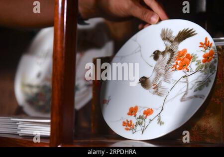 (190805) -- NANCHANG, Aug. 5, 2019 -- Mao Guanghui places a piece of porcelain painting on the shelf at his studio in Jingdezhen, east China s Jiangxi Province, Aug. 1, 2019. Mao Guanghui, a 56-year-old senior master of arts and crafts in Jiangxi Province, has been devoting himself to porcelain painting since the age of 13. As a third-generation disciple of Deng Bishan (1874-1930), one of the Eight Friends of Zhushan , a group of Jingdezhen artisans widely noted for their innovations in porcelain painting, Mao inherited not only the skills but also the art of creating porcelain painting pieces Stock Photo