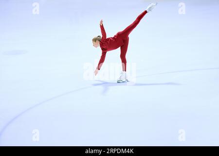 Talented girl, teenager in red sportswear, figure skating athlete in motion, training on ice rink arena Stock Photo