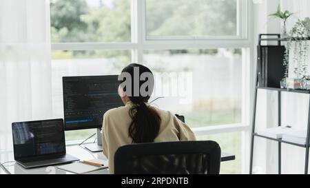 Back of developer programmer programming code to developing web and application in software office. Stock Photo