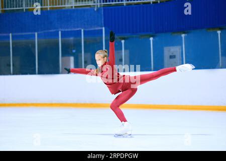 Talented, hardworking and concentrated girl, figure skating athlete in motions, training on ice rink arena Stock Photo