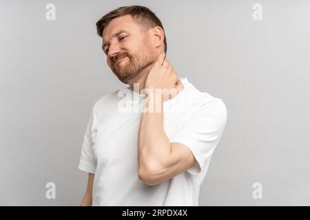 Unhealthy man suffering painful neck ache after sports exercise. Back pain and hernia, sedentary.  Stock Photo