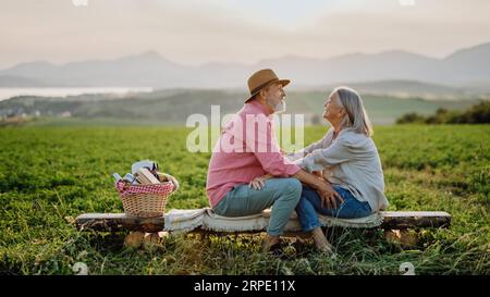 Elderly spouses looking at each other with serene landscape of High Tatras behind them. Stock Photo