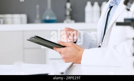 Laboratory scientist typing on a digital tablet and examining a dna test reaction to monkeypox virus during medical research. Biochemical engineer Stock Photo