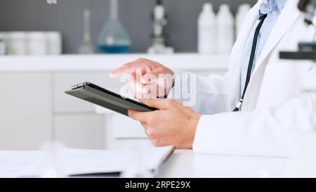 Laboratory scientist scrolling on a digital tablet and examining a dna test reaction to monkeypox virus during medical research. Biochemical engineer Stock Photo