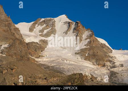 Gran Paradiso mountain and glacier view from chabod hut at sunset. golden hour, colored peak against blue sky. landscape Stock Photo