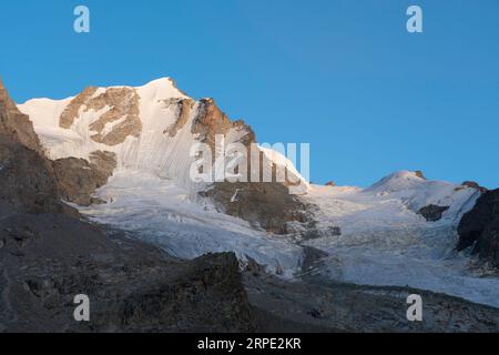 Gran Paradiso mountain and glacier view from chabod hut at sunset. golden hour, colored peak against blue sky. landscape Stock Photo