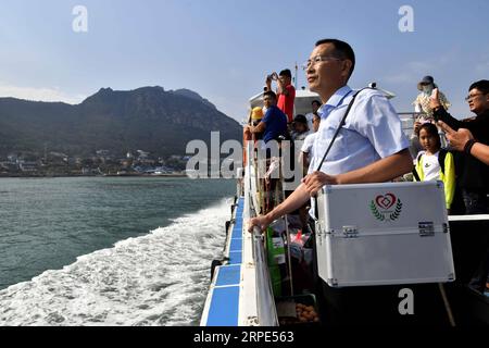 (190818) -- QINGDAO, Aug. 18, 2019 -- Doctor Zhou Zhaojing takes a boat to the Lingshan Island of Qingdao, east China s Shandong Province, Aug. 16, 2019. The Lingshan Island is located some nine sea miles southeast off the west coast of Qingdao. Since 2013, the west coast new area has dispatched medical staff members to work by turns on the island. The 40-year-old Zhou was selected in 2018 as a general practitioner to work at the island s health service center. Despite harsh working and living conditions, Zhou and his colleagues never get slack at their work to provide medical service to some Stock Photo