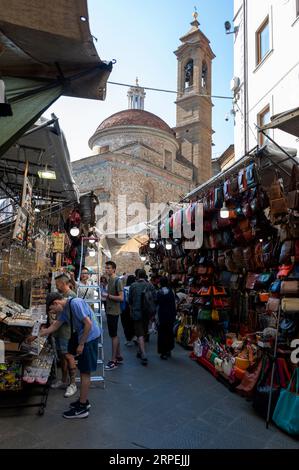 Market traders preparing to open the local leather goods market near the Renaissance church of the Basilica di San Lorenzo ((Basilica of St. Lawrence) Stock Photo