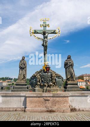 Metal crucifix scene installed in 17th century on Charles Bridge is flanked by 19th century sandstone statues of Mary and John the Evangelist. The Heb Stock Photo