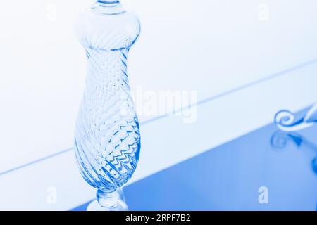 Transparent empty vase over light blue wall background. Abstract glass installation Stock Photo