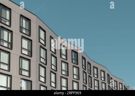 Side view of a hotel building with many windows and metal facade in a minimalistic style against a blue sky Stock Photo