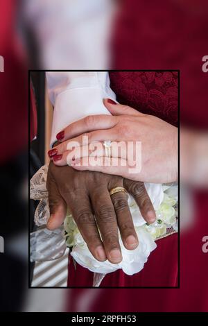 Beautiful portrait of the rings and hands of interracial couple on their wedding day. Stock Photo