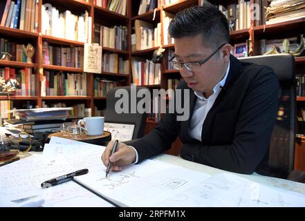 190927 -- BEIJING, Sept. 27, 2019 -- Chen Nan draws a design manuscript at his studio in Tsinghua University in Beijing, capital of China, Sept. 24, 2019. Boasting a history of more than 3,000 years, oracle bone script, the earliest Chinese writing inscriptions carved on tortoise shells and animal scapulas, has been given modern meanings with a new series of emojis, thanks to the efforts made by Chen Nan. Chen, a professor at the Academy of Arts and Design of Tsinghua University, has devoted himself to studying and designing oracle bone script since 1999. So far, Chen has issued six sets of an Stock Photo