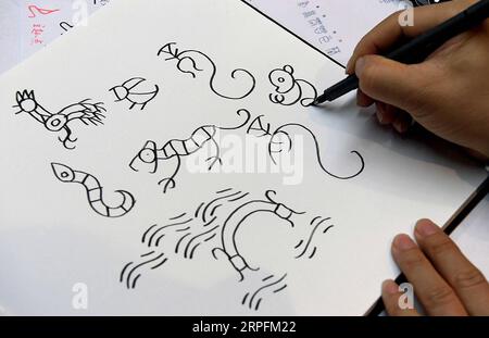 190927 -- BEIJING, Sept. 27, 2019 -- Chen Nan draws a design manuscript at his studio in Tsinghua University in Beijing, capital of China, Sept. 24, 2019. Boasting a history of more than 3,000 years, oracle bone script, the earliest Chinese writing inscriptions carved on tortoise shells and animal scapulas, has been given modern meanings with a new series of emojis, thanks to the efforts made by Chen Nan. Chen, a professor at the Academy of Arts and Design of Tsinghua University, has devoted himself to studying and designing oracle bone script since 1999. So far, Chen has issued six sets of an Stock Photo